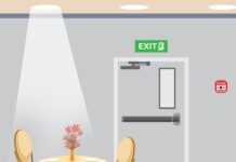 After the Correspondents’ Dinner Shooting, Trump Changes Tone Round dining table set for four under a spotlight, with a pink flower centerpiece, in a banquet room beside an exit door.